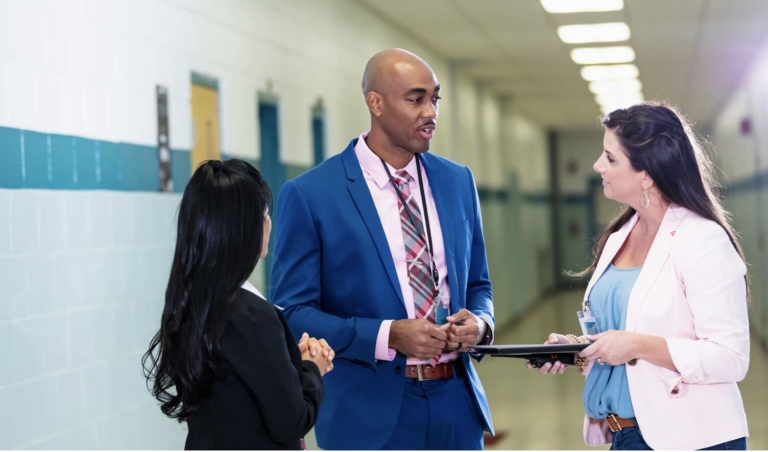 prinicpal speaking to two teachers in hallway