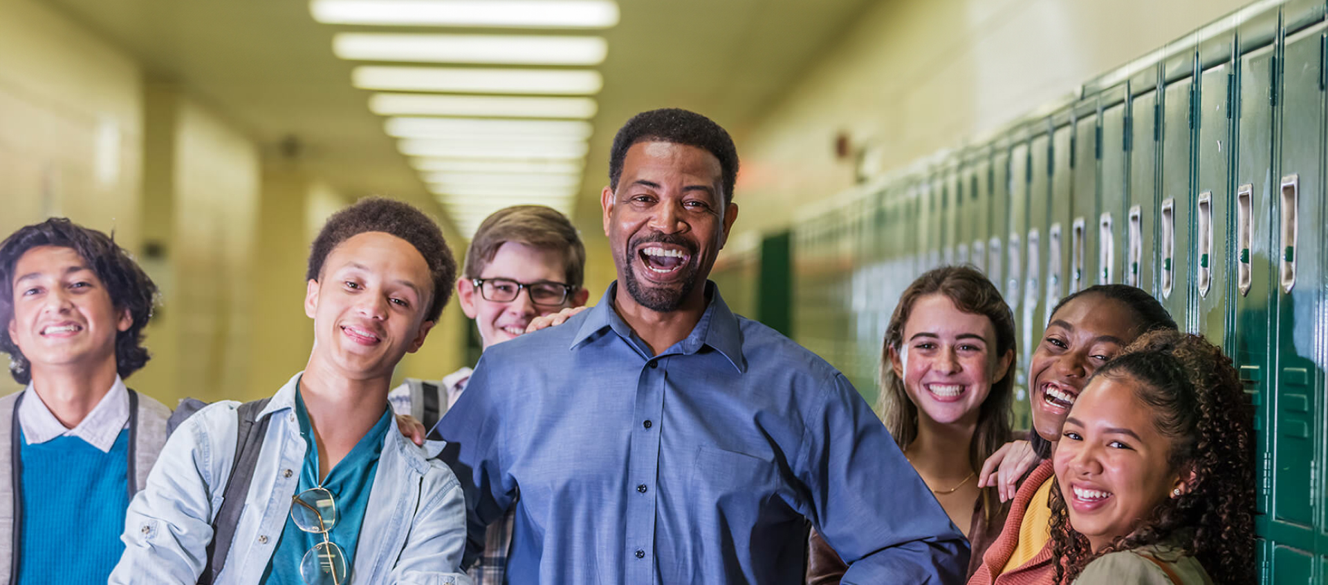 smiling teacher with students in hallway